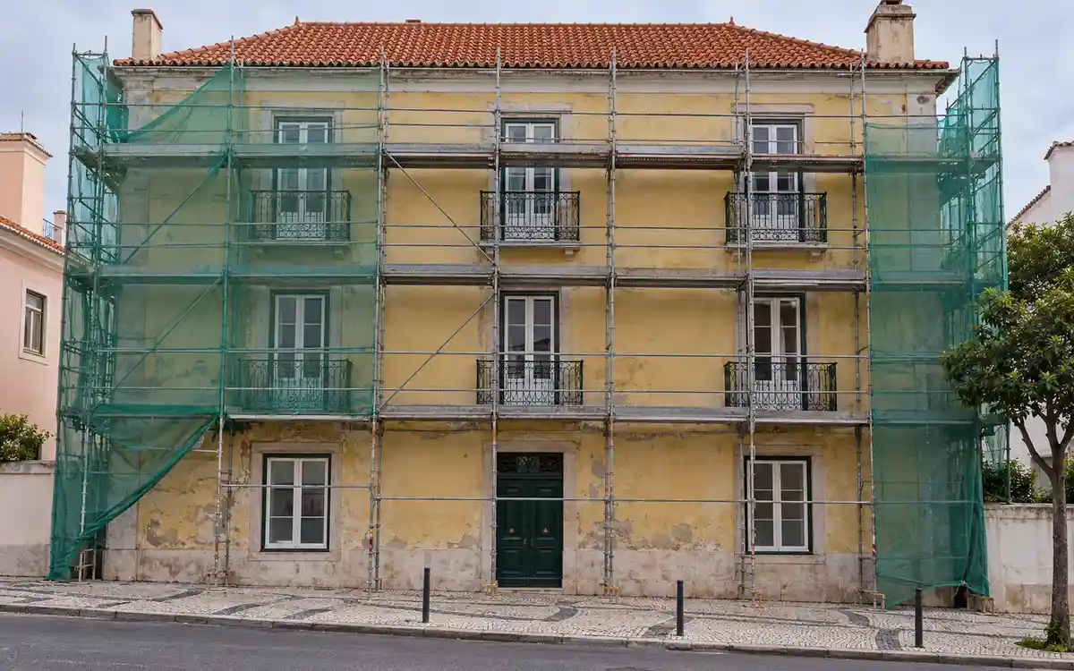 Imagem ilustrativa de um prédio antigo junto ao centro de Cascais, com andaime na fachada e telhado de telha